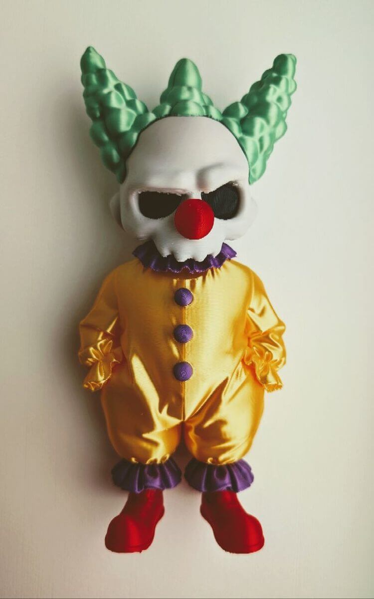 Clown figure with a skull face, glossy yellow suit, and green details