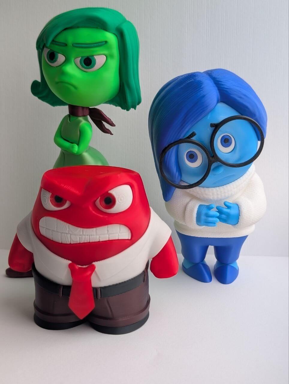 Three colorful cartoon character figures in green, red, and blue
