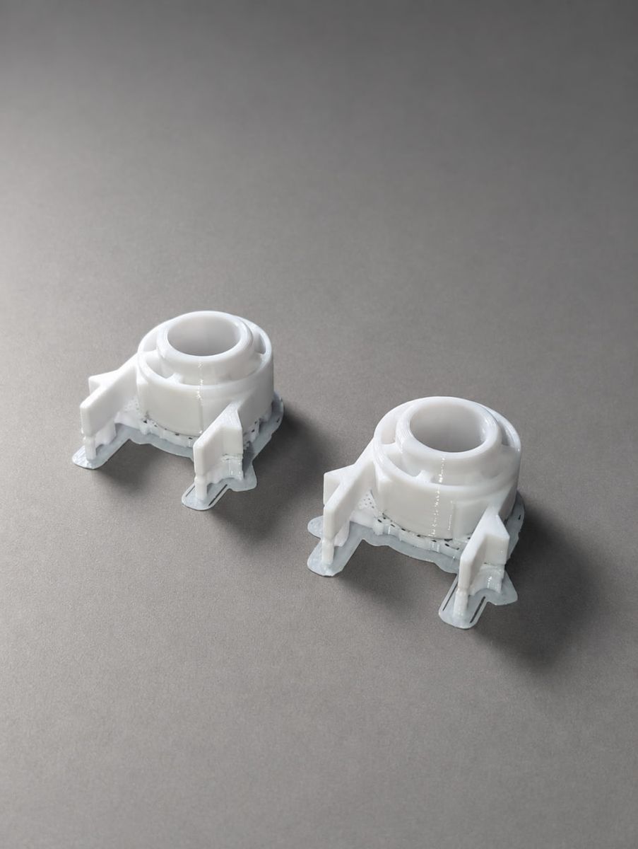 Two identical freshly printed parts still attached to their print supports
