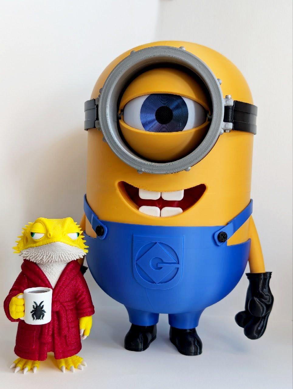 Large Minion figure with a detailed mechanical eye beside a small lizard character in a red coat