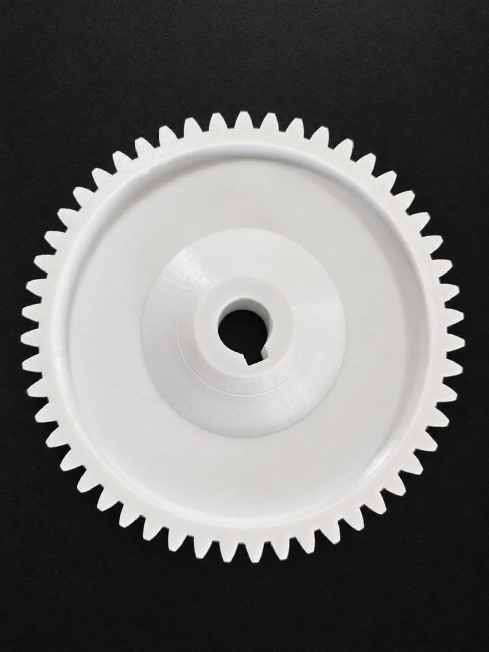White 3D-printed gear photographed on a black background