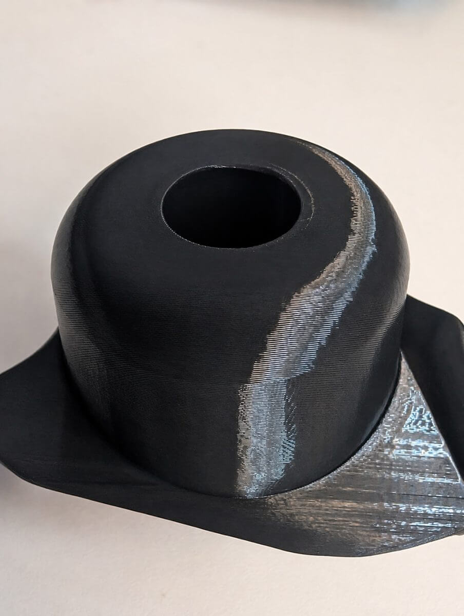 Close-up of a dark 3D-printed part showing a change in surface texture and print angle