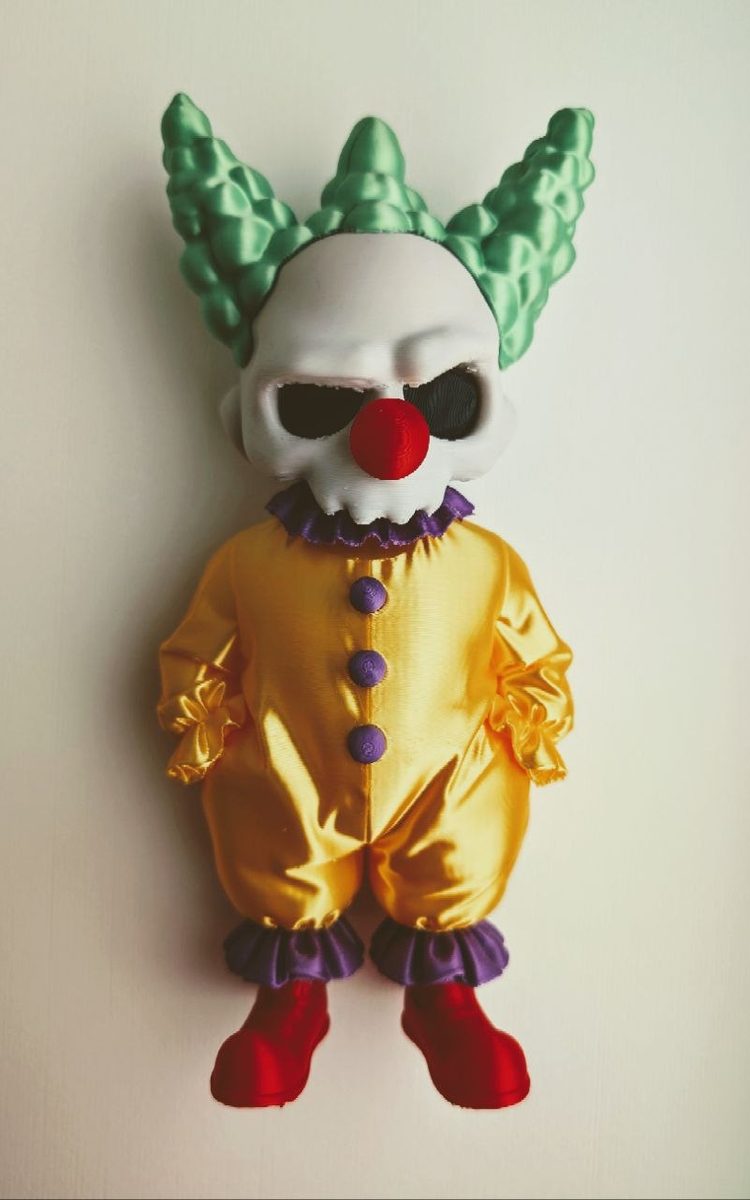 Clown figure with a skull face, glossy yellow suit, and green details