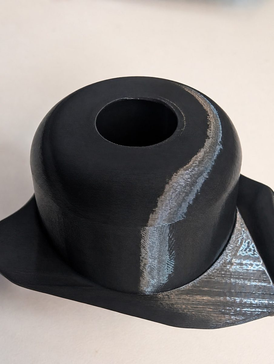 Close-up of a dark 3D-printed part showing a change in surface texture and print angle